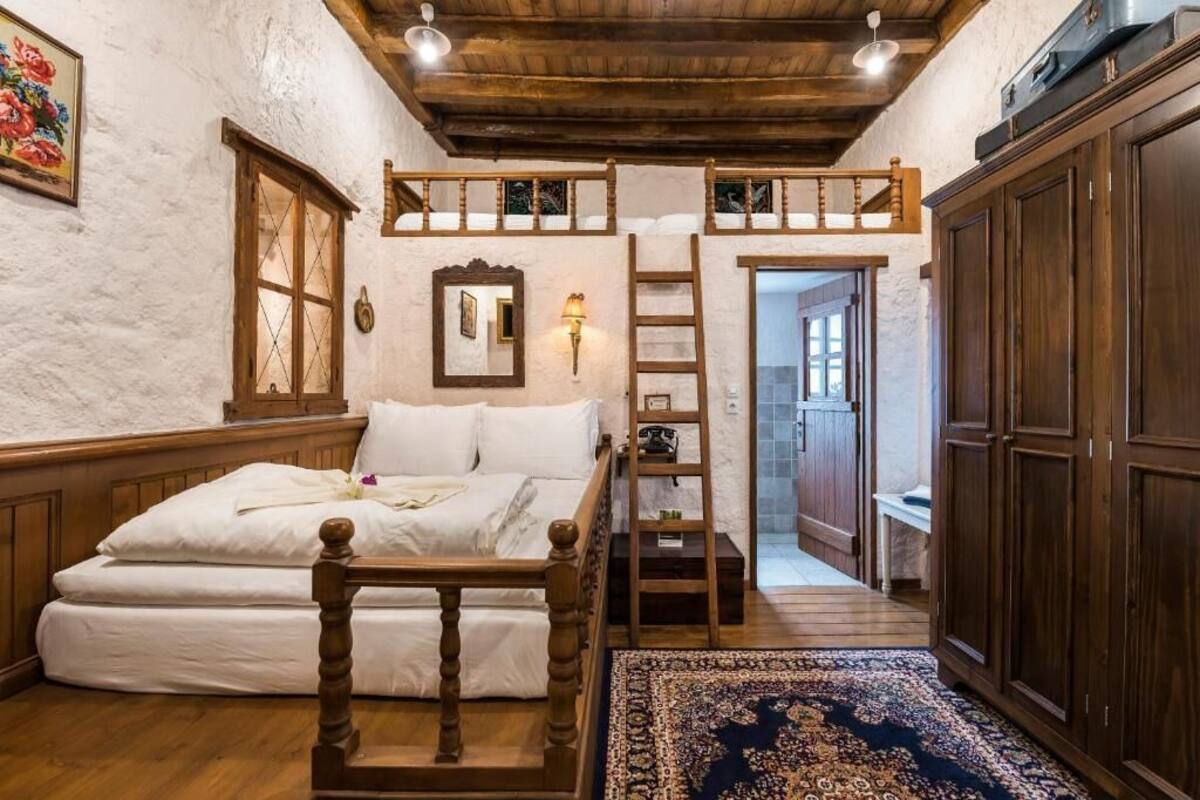 A bedroom with a wooden bed, a ladder, a wardrobe, and a large window.
