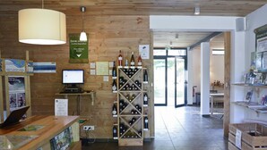 Een houten interieur met een receptiebalie, een computer, een wijnrek en informatieposters.