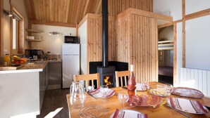 Een gezellig interieur van een blokhut, met houten inrichting, een keuken en een eettafel gedekt voor een maaltijd.