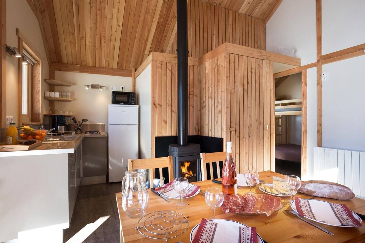 Ein gemütliches Blockhäuschen im Inneren, mit Holzvertäfelung, einer Küchenzeile und einem Essplatz, der für eine Mahlzeit gedeckt ist.