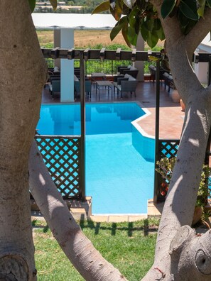 Ein Poolbereich mit Pergola, Gartenmöbeln und Blick auf die umliegende Landschaft.