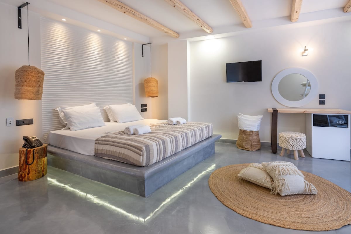 Une chambre à coucher moderne avec un grand lit, des tables de chevet, une télévision et un miroir.