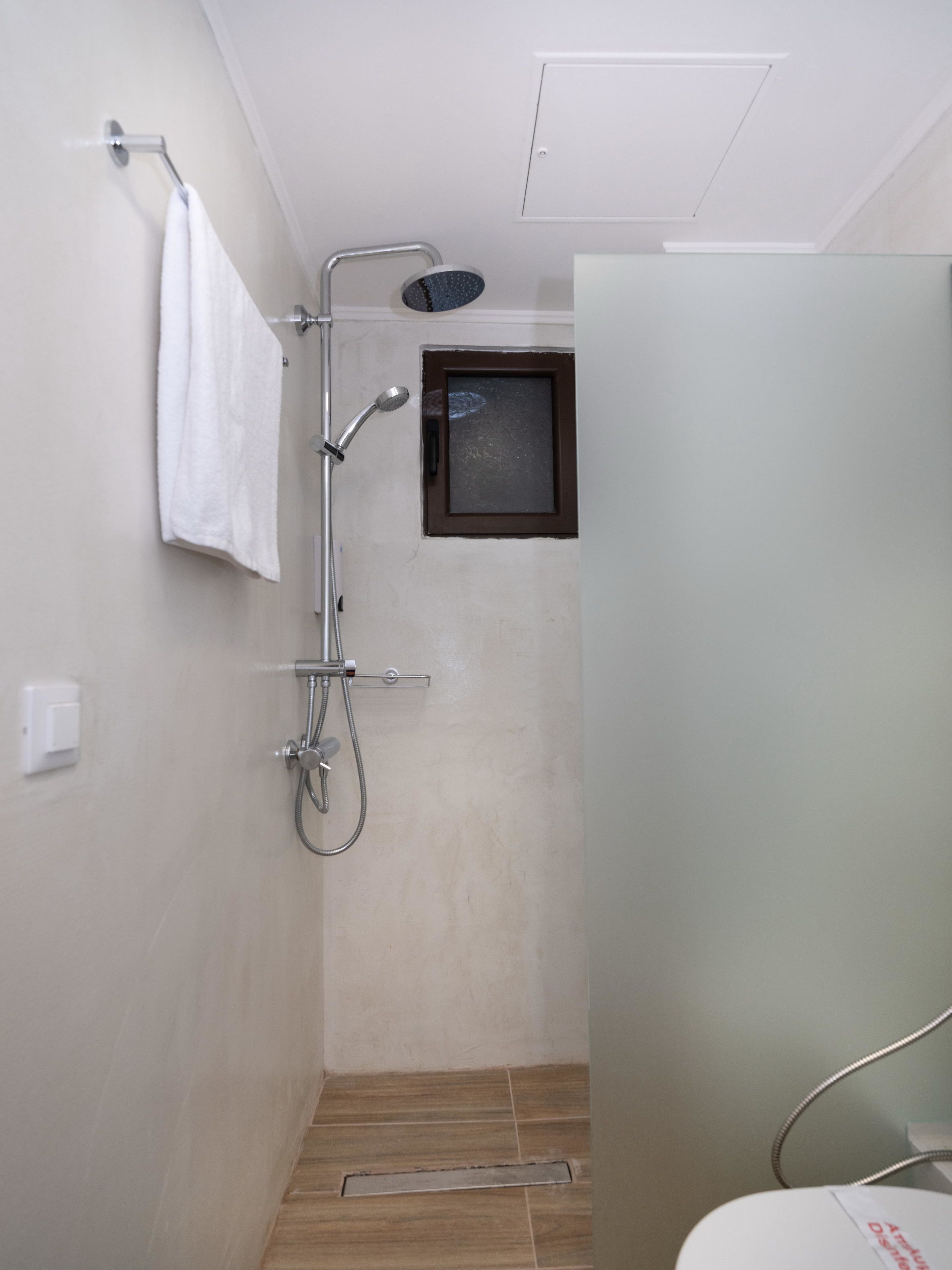 Un espacio de ducha pequeño y cerrado con cabezal de ducha manual y panel de control en la pared.