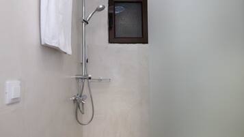 Un espacio de ducha pequeño y cerrado con cabezal de ducha manual y panel de control en la pared.