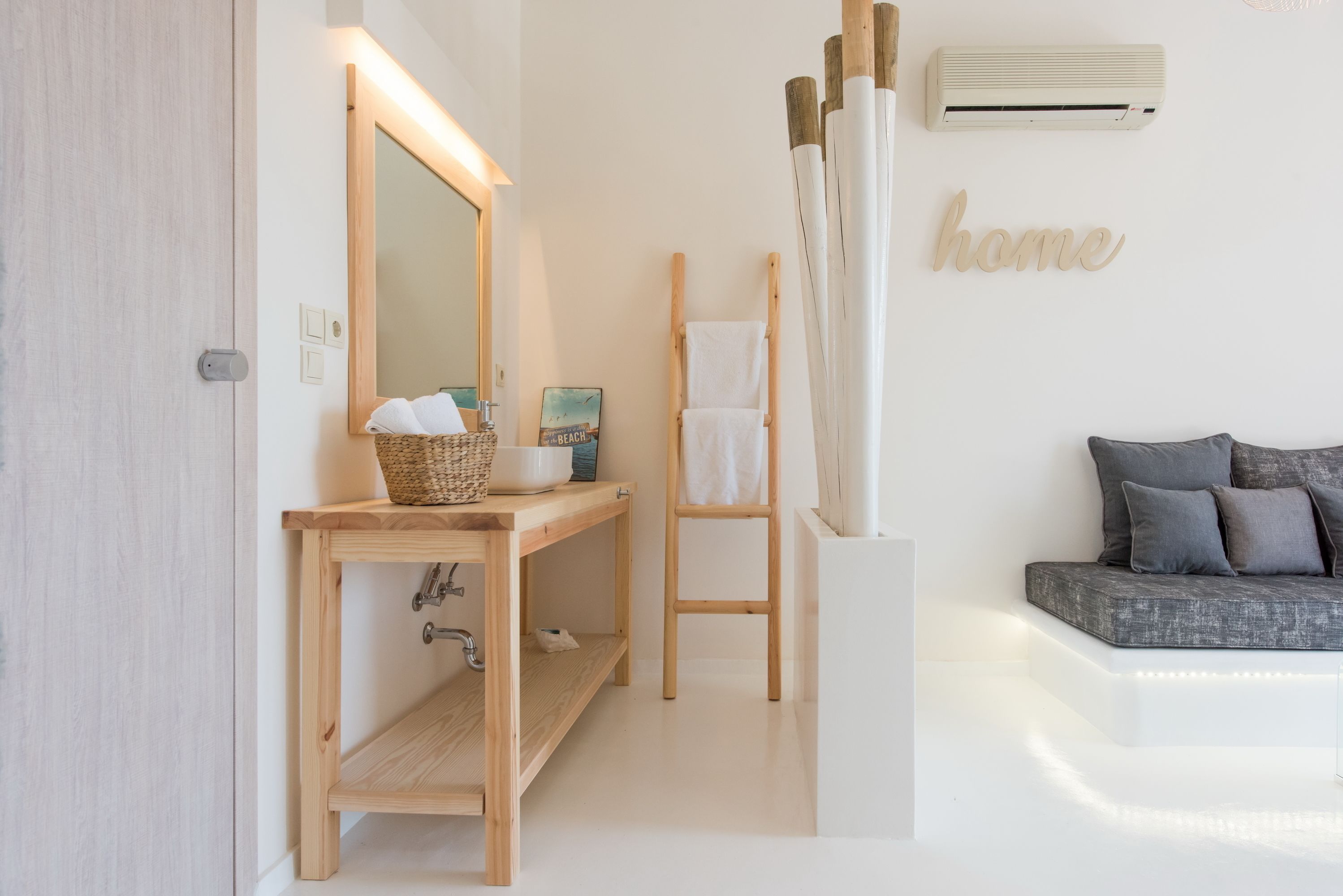 A modern bathroom with a wooden vanity, a large mirror, a towel rack, and a wall-mounted air conditioner.