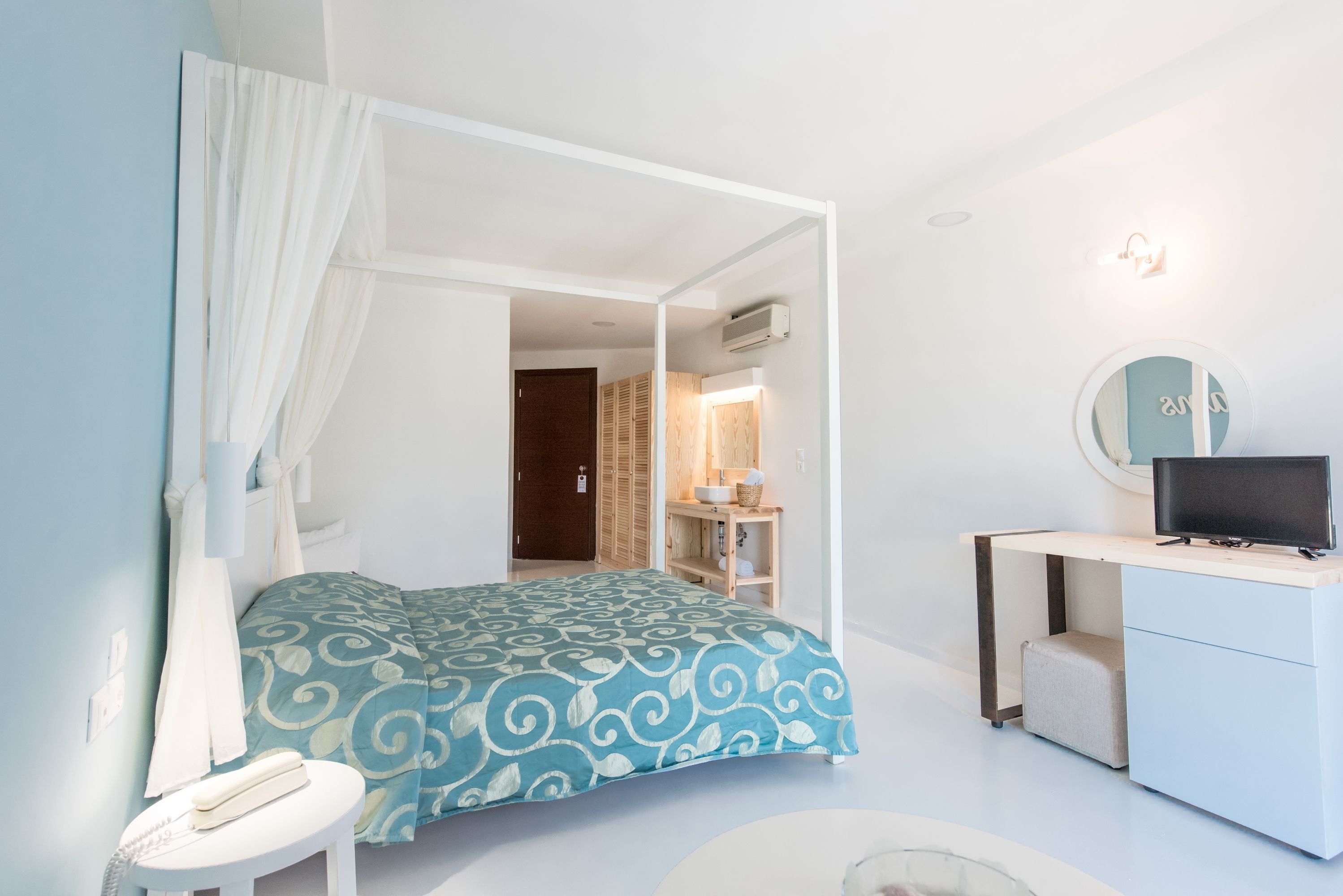 A bedroom with a bed, bedside table, and a desk with a computer.