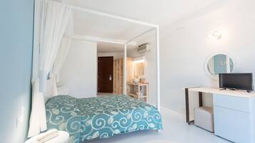 A bedroom with a bed, bedside table, and a desk with a computer.