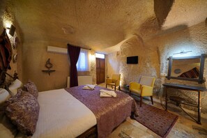 A cozy bedroom with a large bed, two chairs, a small table, and a mirror on the wall. - Emit Cave Hotel (Nevsehir)