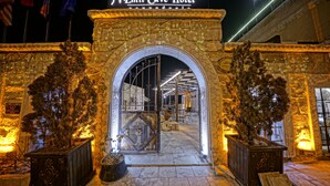 The entrance to the Emit Cave Hotel with a stone archway, potted plants, and flags. - Emit Sakura Cave Hotel (Nevsehir)