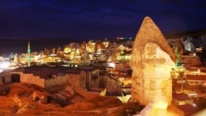 A nighttime view of a historic town with illuminated buildings and a prominent rock formation. - Emit Sakura Cave Hotel (Nevsehir)