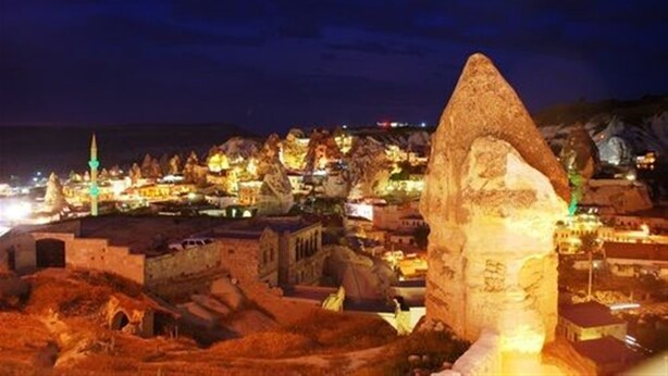 A nighttime view of a historic town with illuminated buildings and a prominent rock formation. - Emit Sakura Cave Hotel (Nevsehir)