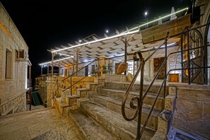 A stone staircase leading to a covered area with metal railings and a view of a building with a wooden door. - Emit Cave Hotel (Nevsehir)