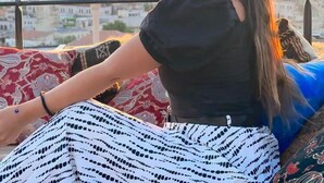 A person sitting on a balcony with a cityscape and hot air balloons in the background. - Emit Sakura Cave Hotel (Nevsehir)