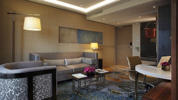 Et moderne hotelværelse med en sofa, et sofabord, et skrivebord og en lampe.