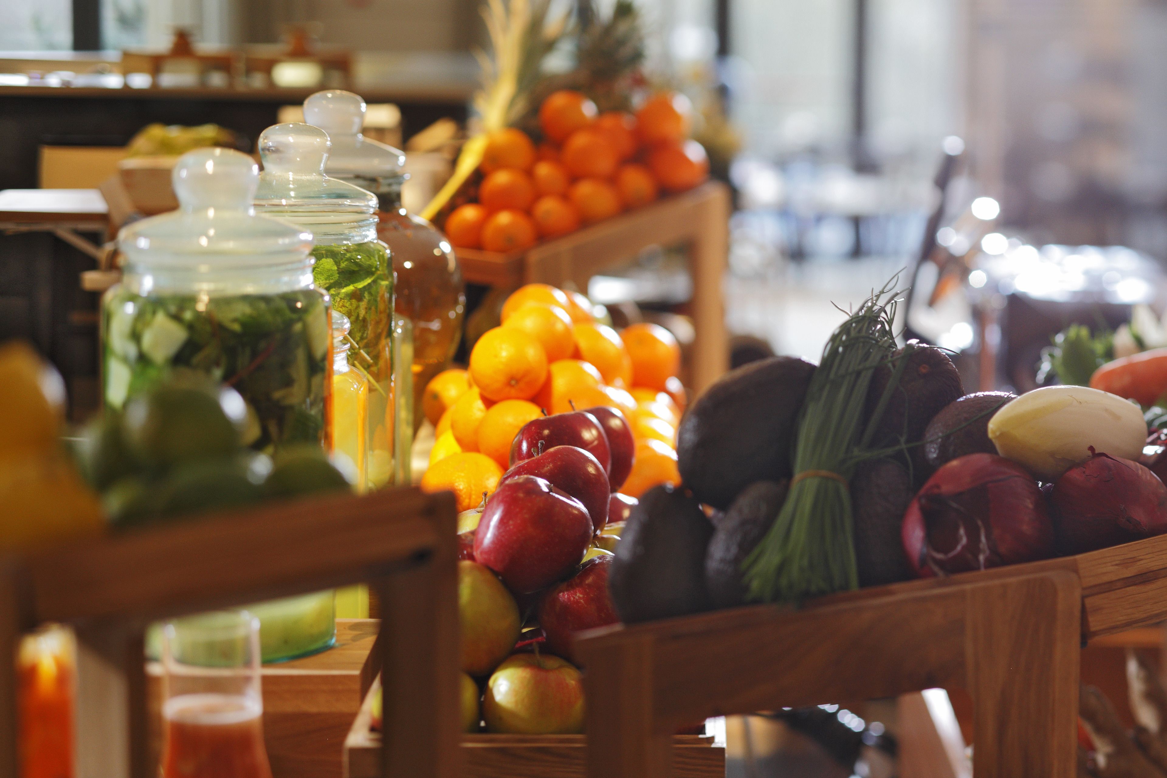 A wooden table with various fruits and vegetables, including apples, oranges, and avocados.