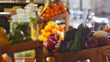 A wooden table with various fruits and vegetables, including apples, oranges, and avocados.