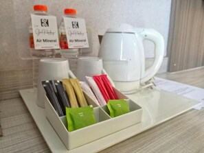 Una bandeja con bolsitas de té, un hervidor y dos botellas de agua mineral.