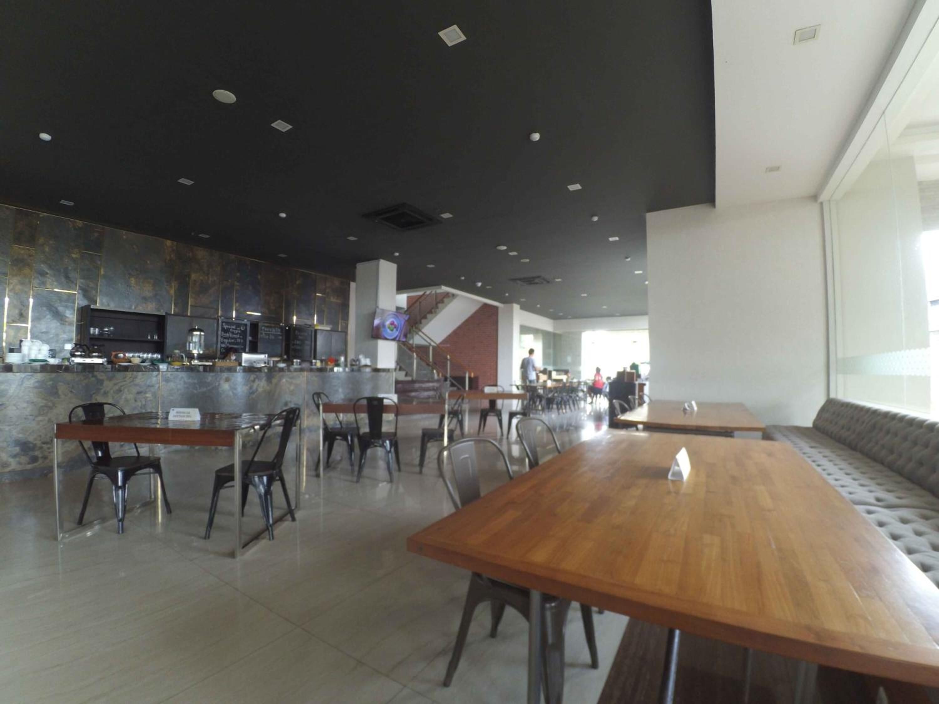 A modern restaurant with a bar area, seating arrangements, and a staircase leading to an upper level.