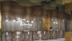 Zona de recepción de un hotel con una pared de mármol y un cartel que dice 'Grand Kolping Hotel'.