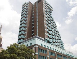 Un edificio de gran altura con varios pisos, que combina fachadas de ladrillo y vidrio.