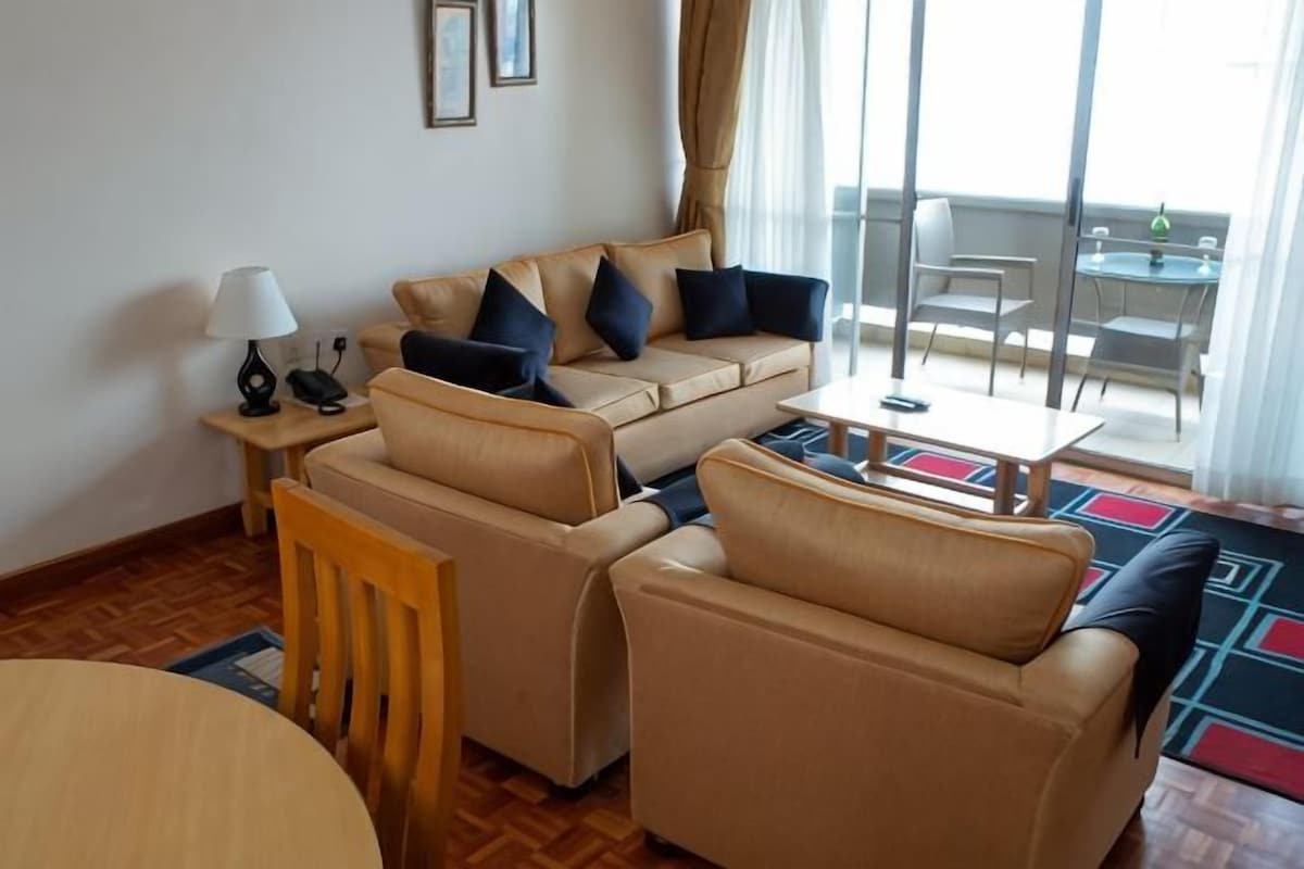 A furnished living room with a sofa set, a table, and a lamp.
