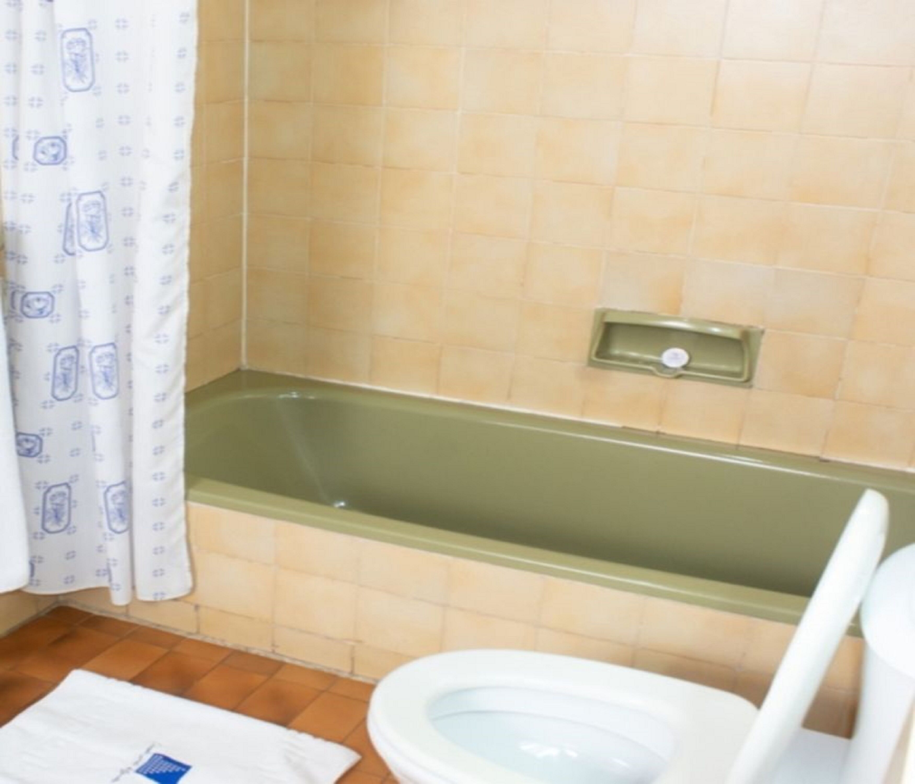 A bathroom with a bathtub, a toilet, and a shower curtain.