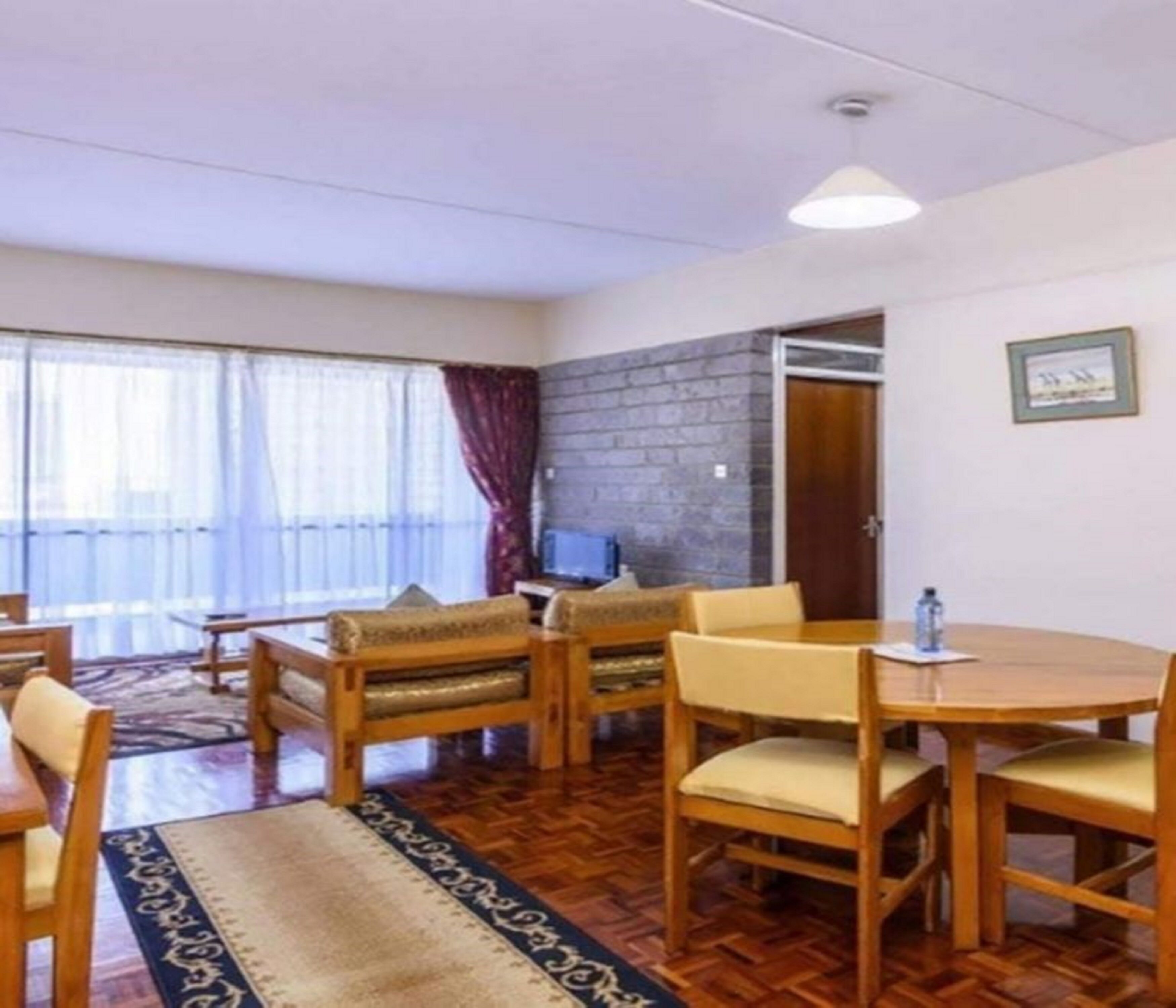 Una habitación con una mesa y sillas de madera, un televisor y una pared de piedra.