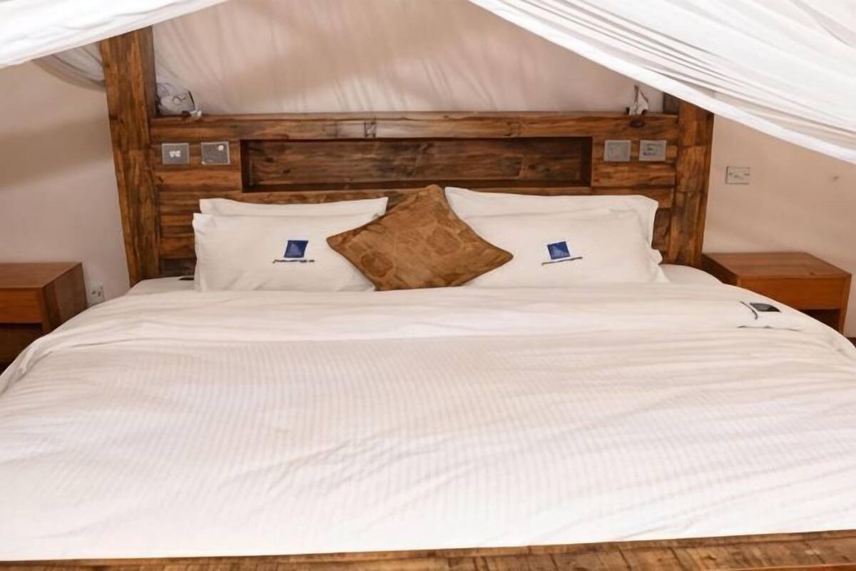 Una cama con cabecera de madera, ropa de cama blanca y dosel.