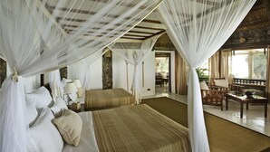 Une chambre avec deux lits, un coin salon avec une table et des chaises, et une vue sur l’extérieur.