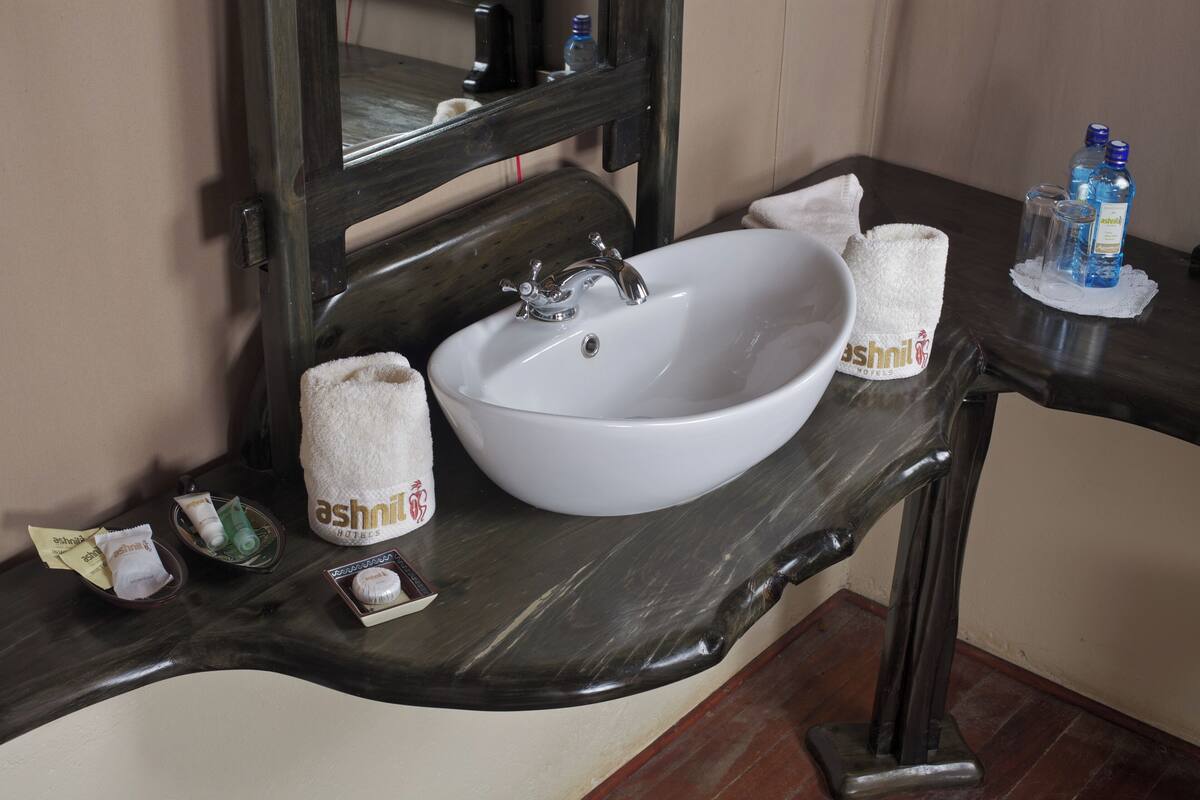 Un baño con lavamanos blanco, un espejo y artículos de tocador en la encimera.