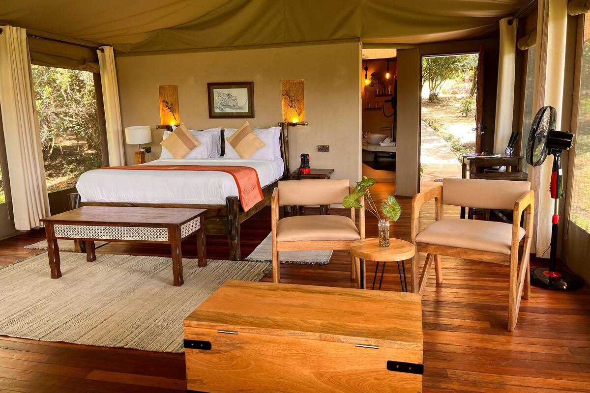 Una habitación con carpa, una cama, muebles de madera, una mesita y una silla.