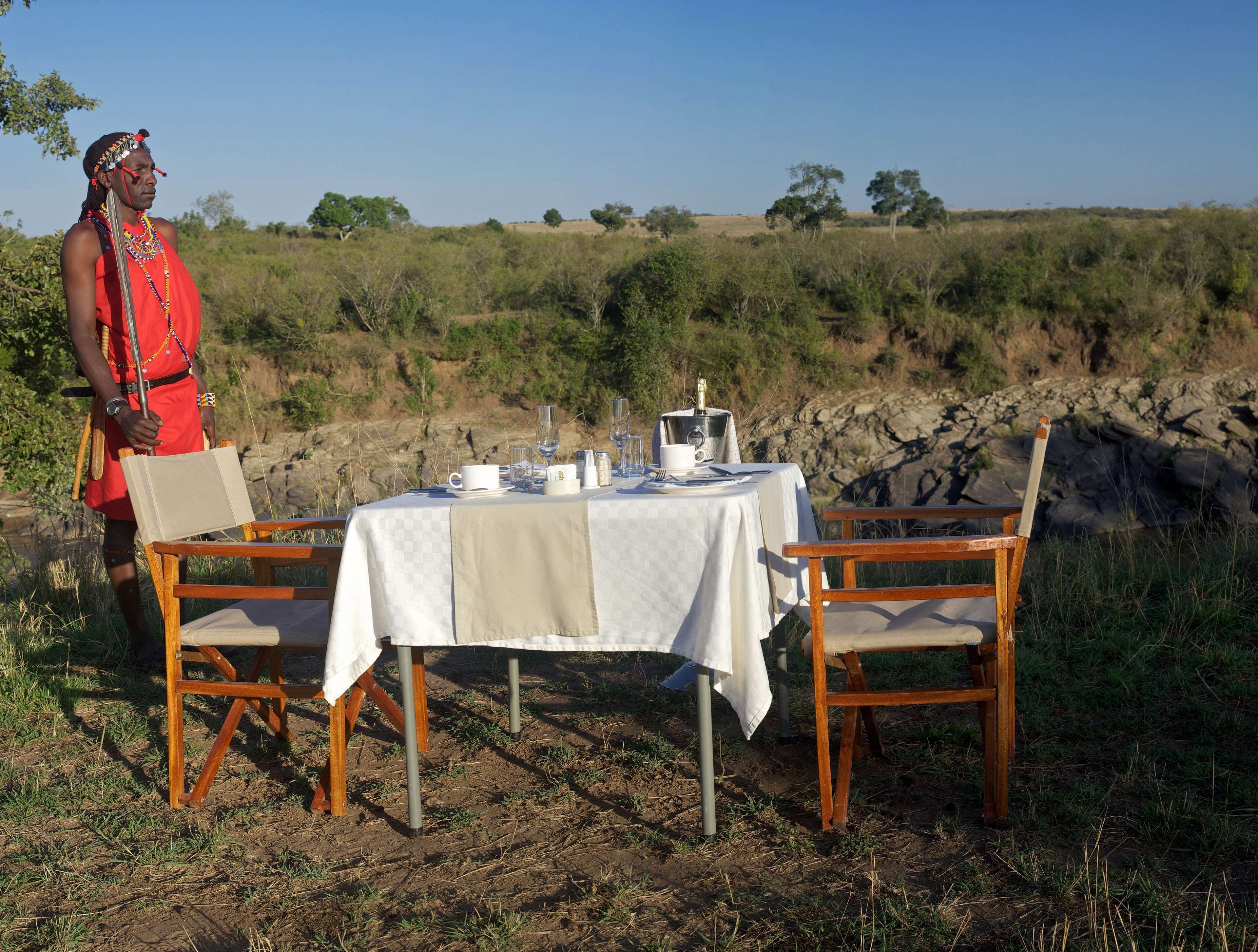 Un espacio para comer al aire libre con una mesa dispuesta para dos personas, rodeado de entorno natural.