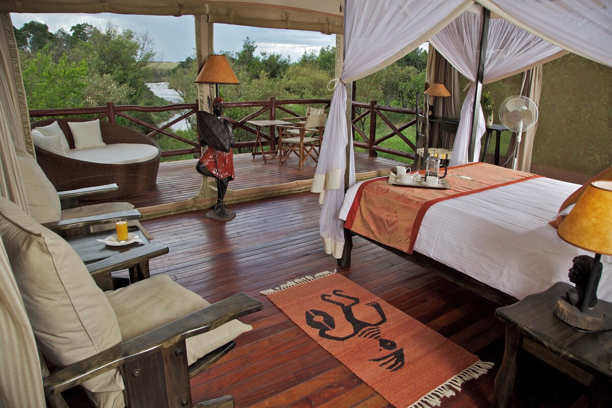 A bedroom with a bed, a sofa, a table, and a fan.