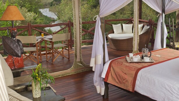 A tented room with a bed, a table with a lamp, and a chair. - Ashnil Mara Camp (Maasai Mara)