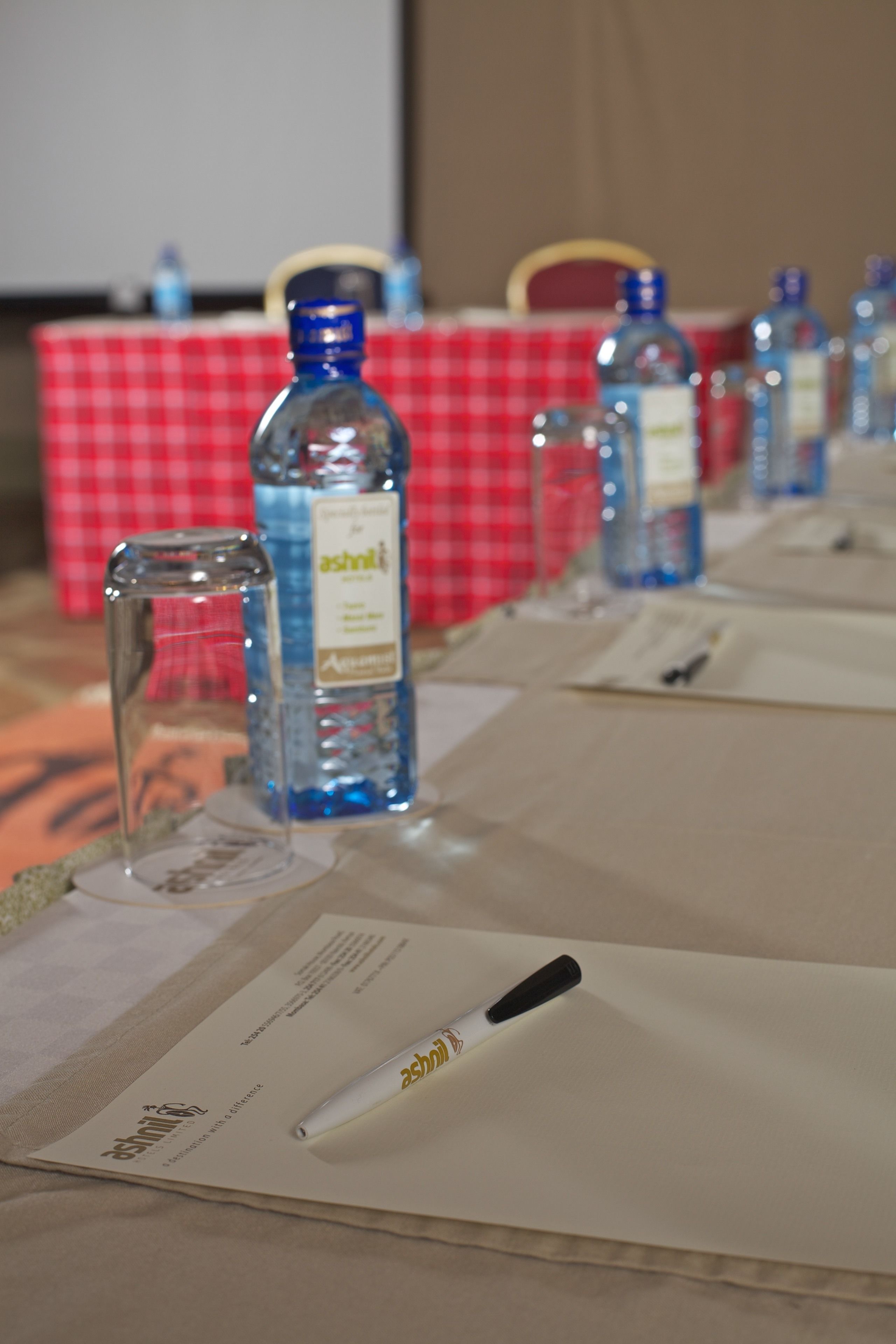 Une table avec des bouteilles et des papiers, probablement préparée pour une réunion ou un événement.