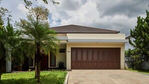 Una casa moderna con garaje, césped cuidado y una palmera.