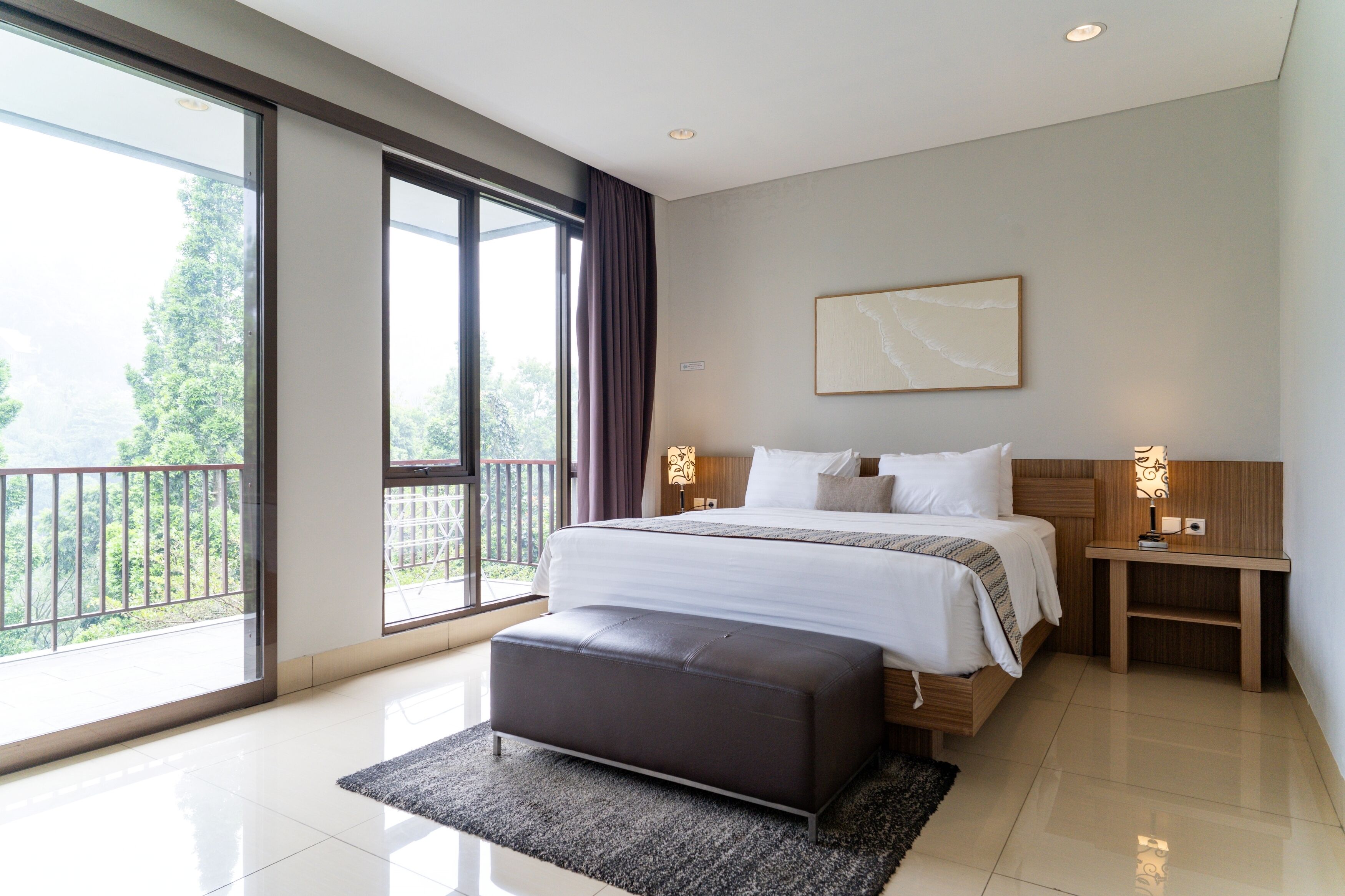 Een moderne hotelkamer met een groot bed, uitzicht door een schuifdeur, een houten nachtkastje en een groot raam.