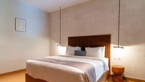 Un dormitorio moderno con estructura de cama de madera, lámpara colgante y un taburete de madera.