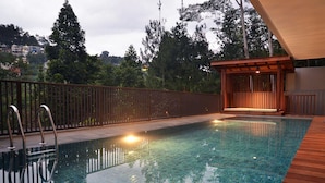 Una piscina con cubierta de madera y un área de descanso techada.