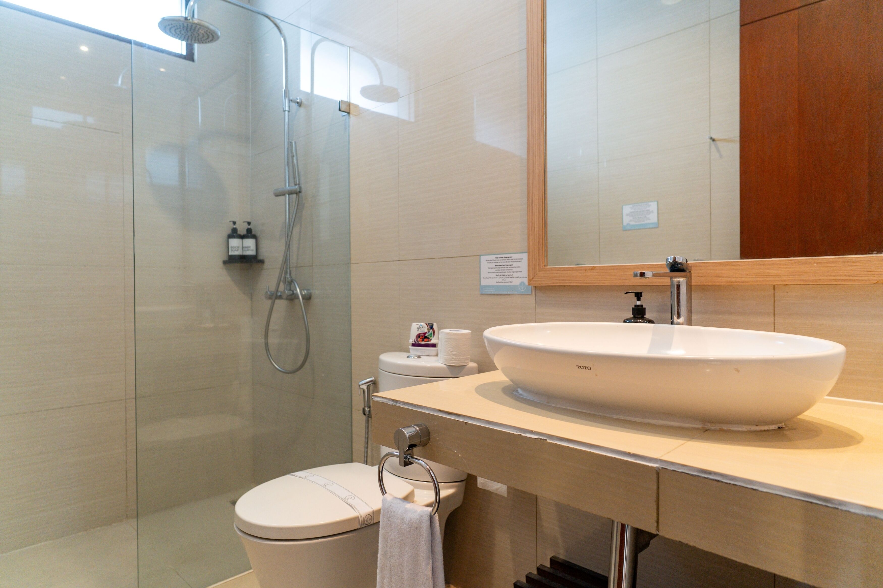 A modern bathroom with a glass-enclosed shower, a white sink, and a toilet.