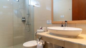 A modern bathroom with a glass-enclosed shower, a white sink, and a toilet.