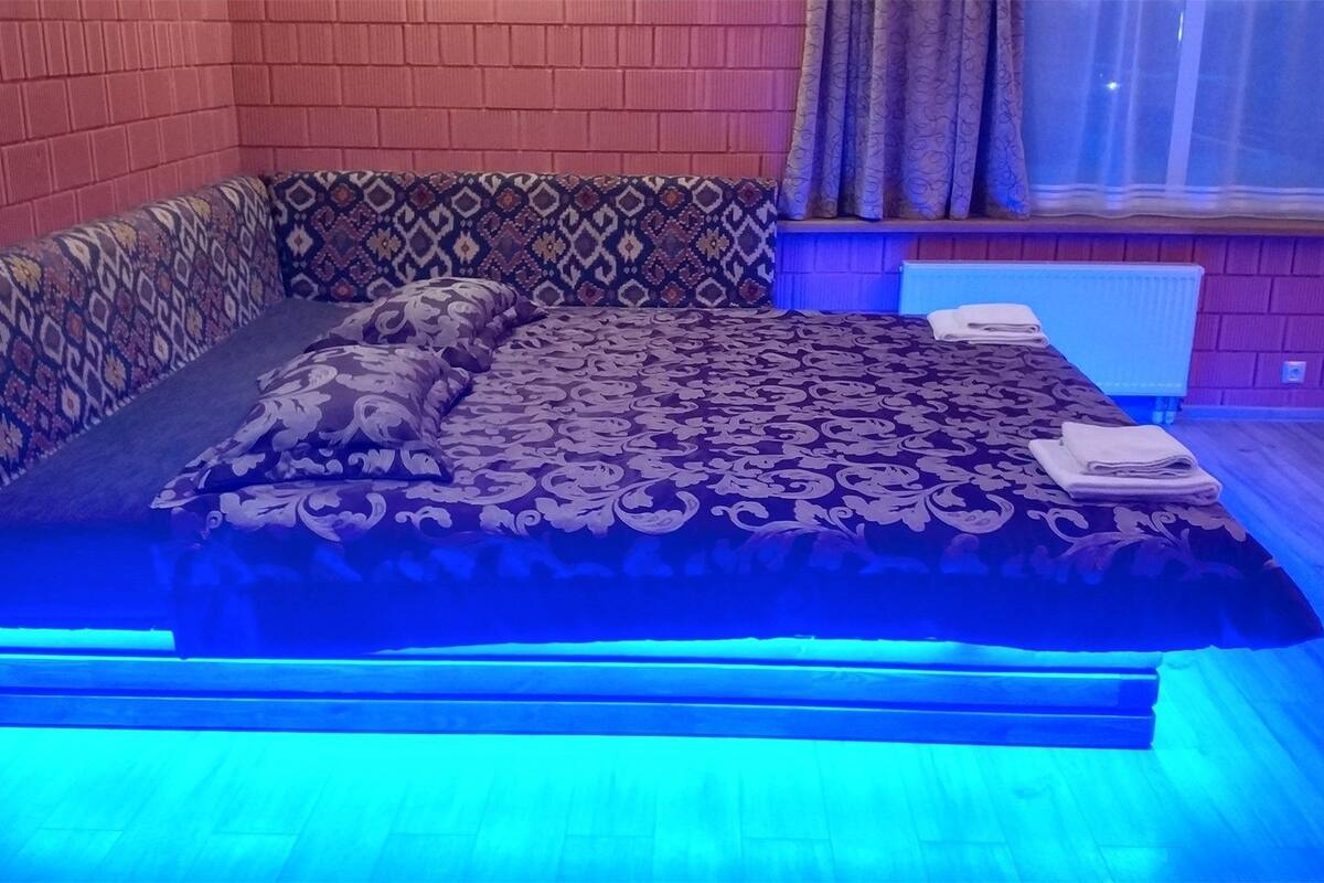 Un lit avec une literie à motifs, un oreiller et une serviette pliée sur un plancher en bois.