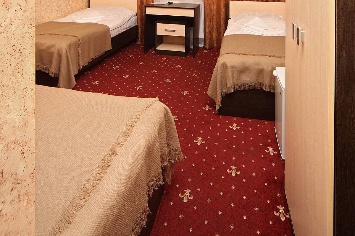 Une chambre d’hôtel avec deux lits simples, une petite table, une chaise et une armoire.