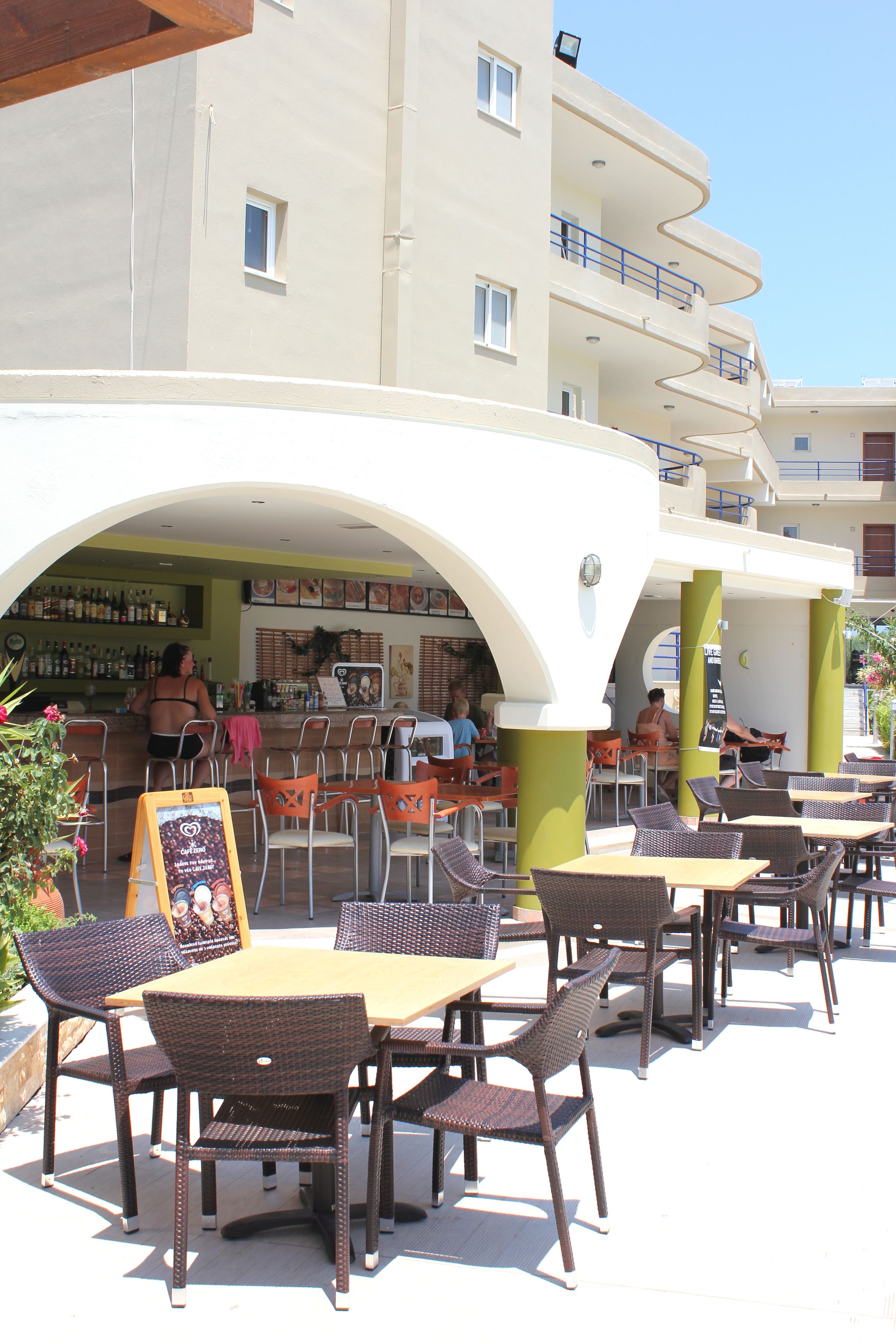 Un espace café en plein air avec des tables et des chaises, un bar et un bâtiment doté de balcons.