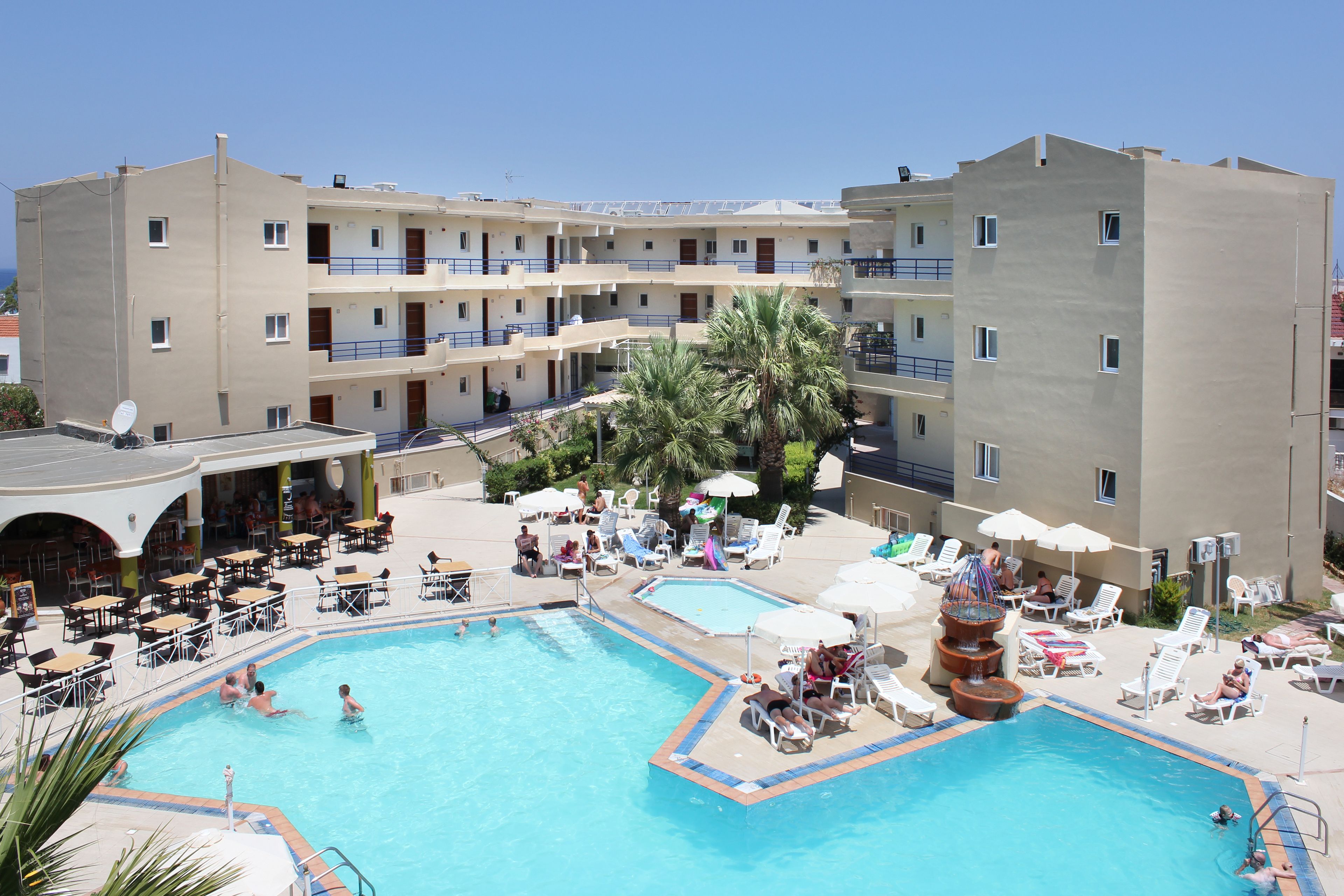 Un hotel con piscina, varios balcones y zonas de estar al aire libre.