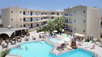 Un hotel con piscina, varios balcones y zonas de estar al aire libre.