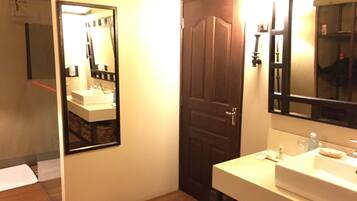 A bathroom with a white sink, a mirror, and a wooden door.