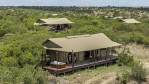 Un lodge de safari doté de plusieurs tentes, chacune comprenant une terrasse en bois et un jacuzzi.