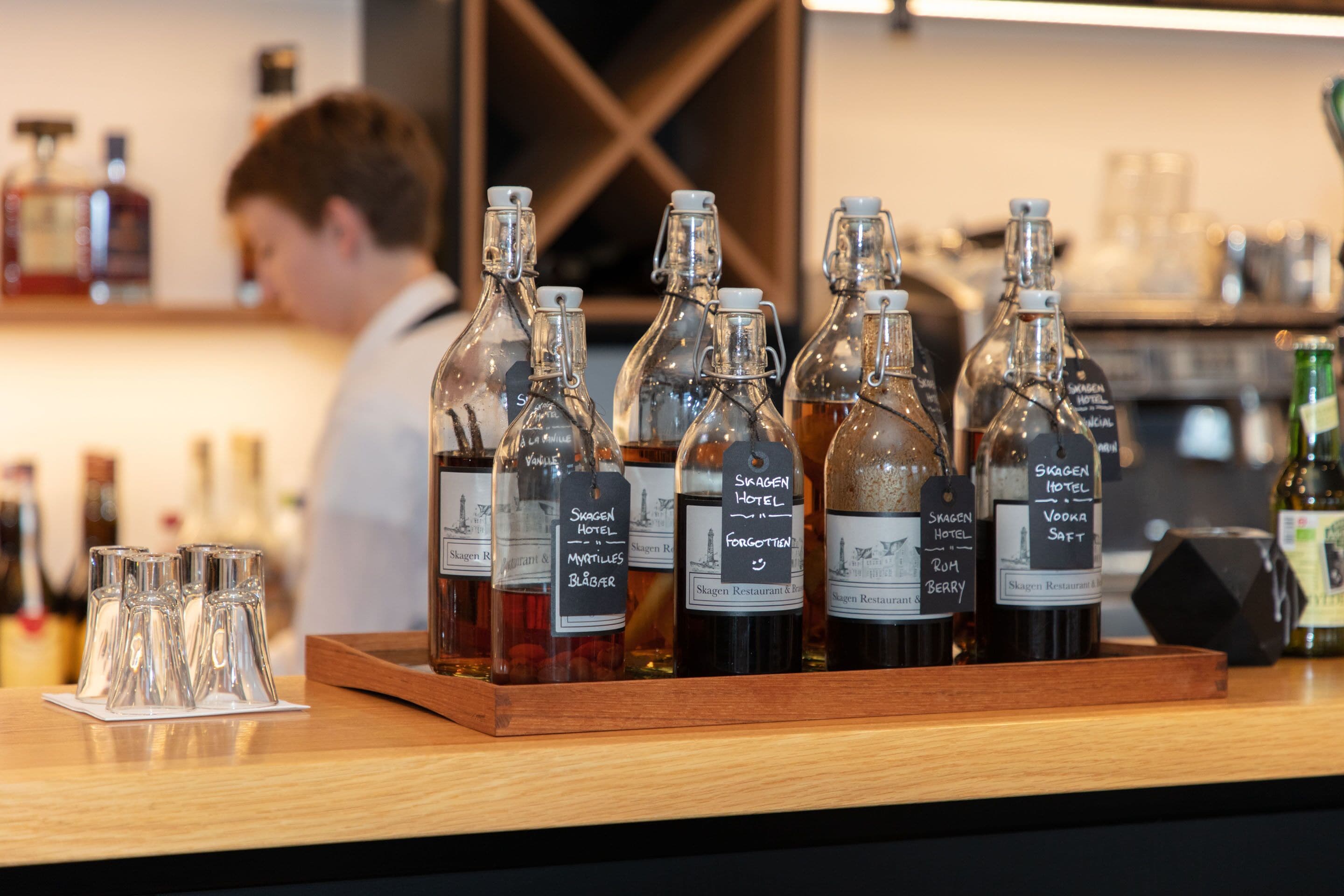 A selection of bottled beverages on a wooden tray with labels indicating they are from Skagen Hotel.