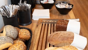 Une table de buffet avec différentes sortes de pains et des ustensiles.